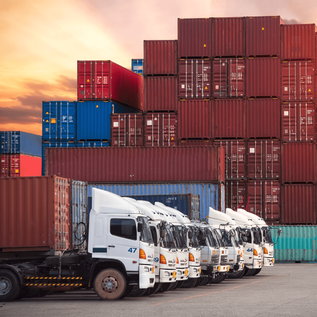 Fleet of trucks lined up in front of stacked shipping containers